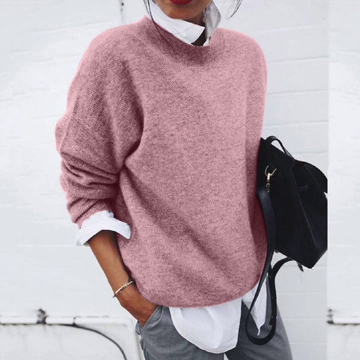 A woman wearing a soft mustard round-neck sweater with an elegant modern shape, relaxed and warm.