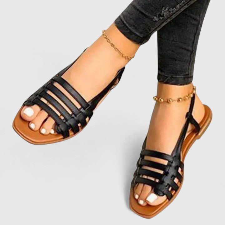 A woman wearing gold refined comfort sandals with a broad, cushioned footbed.