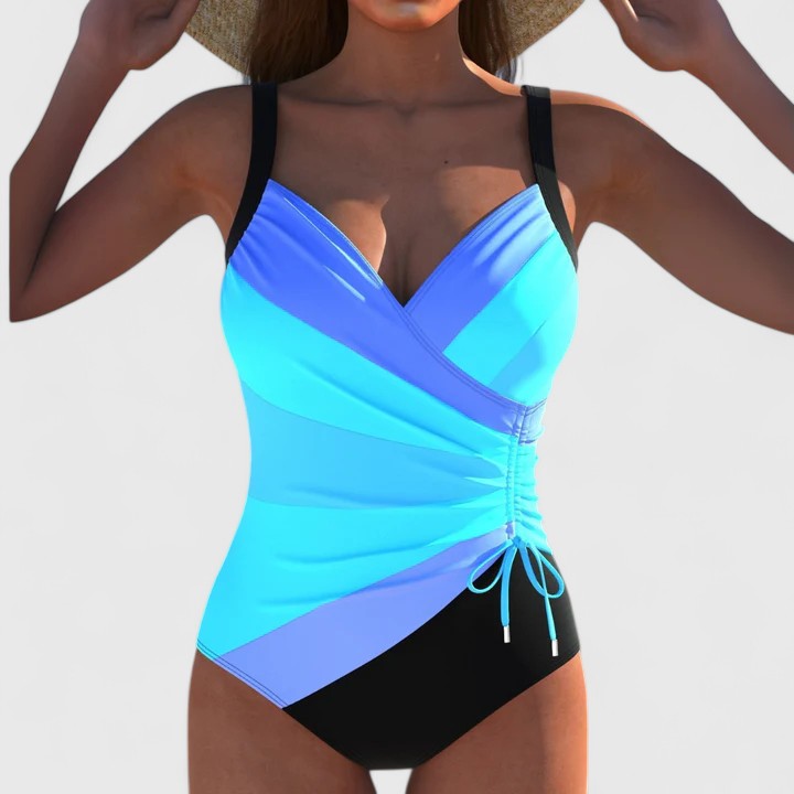 A woman by the water in an elegant printed swimsuit, poised and confident in the summer sun.