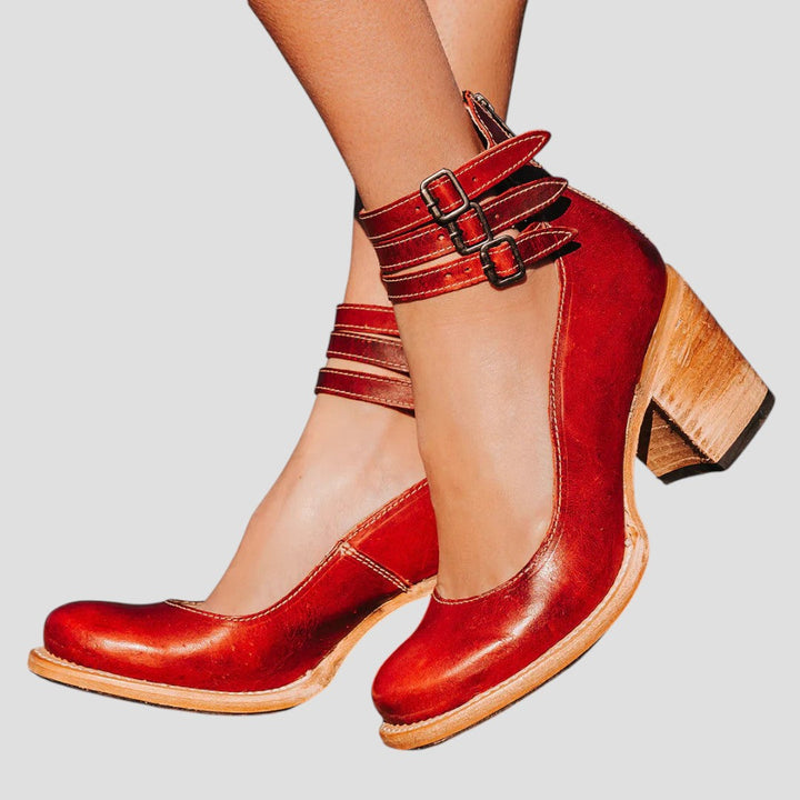 A woman wearing cognac block-heel pumps with triple ankle straps and a rounded toe.