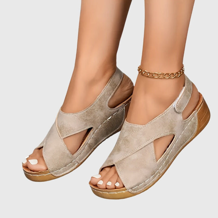 A woman wearing navy cross-strap sandals with a cushioned insole and secure heel fastening.
