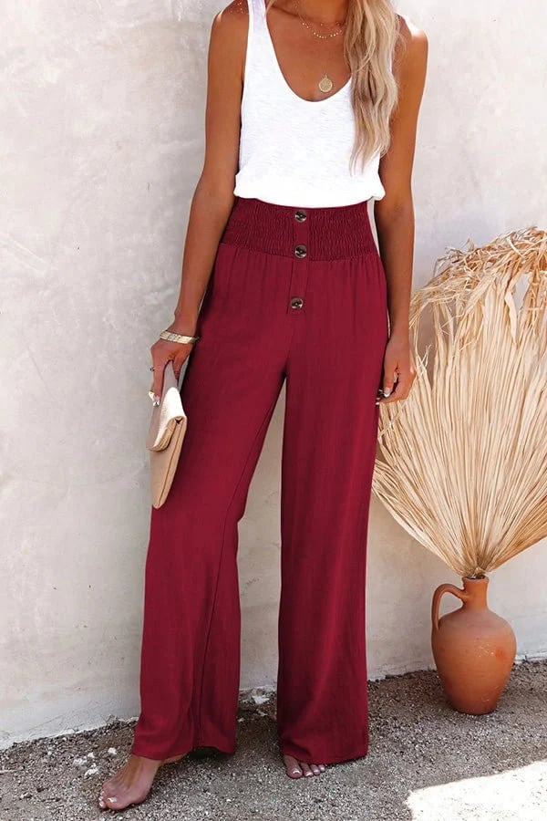 A woman in high-waisted loose wide-leg pants with subtle button detailing, styled for an elegant everyday look.