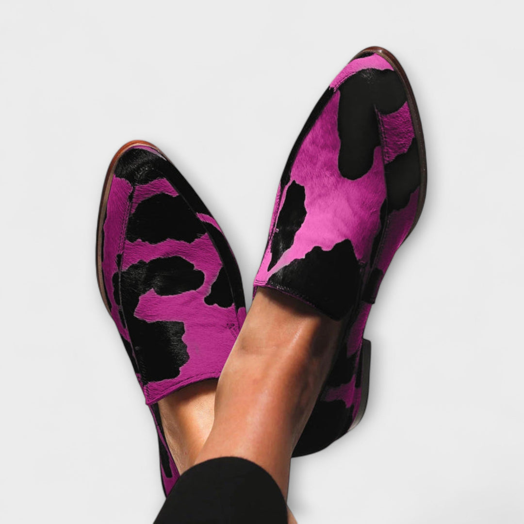 A woman wearing green cow print slip-on loafers, styled for an easy day out.