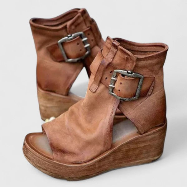A woman in tan buckle wedge sandals, walking easily on a summer afternoon.