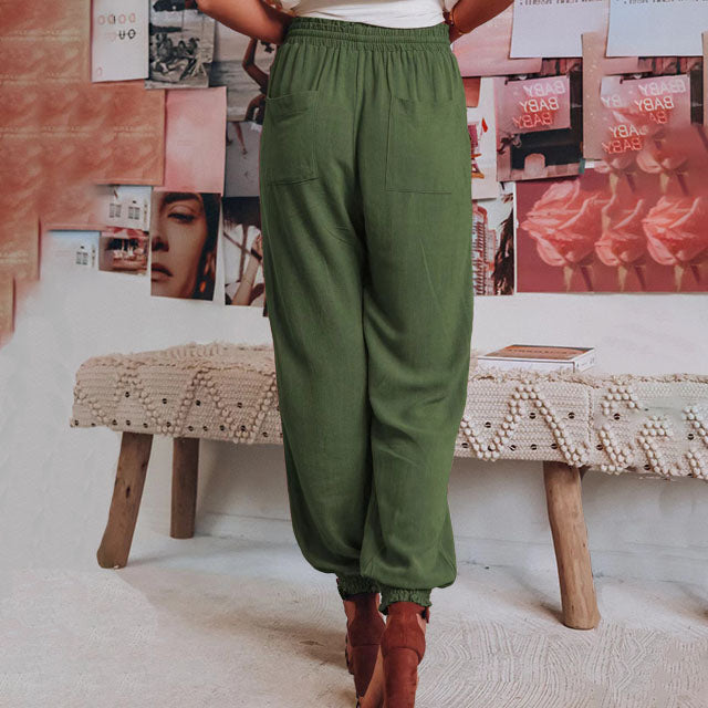 A woman wearing slim tapered black drawstring joggers with a high waist and front patch pockets.