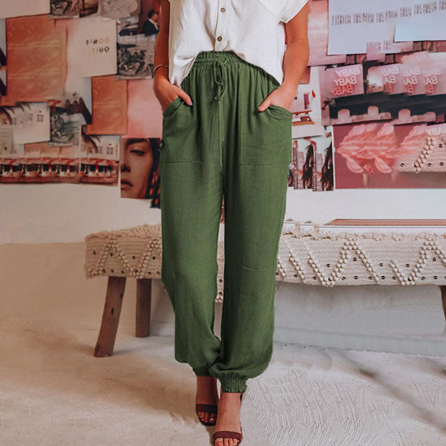 A woman wearing slim tapered black drawstring joggers with a high waist and front patch pockets.