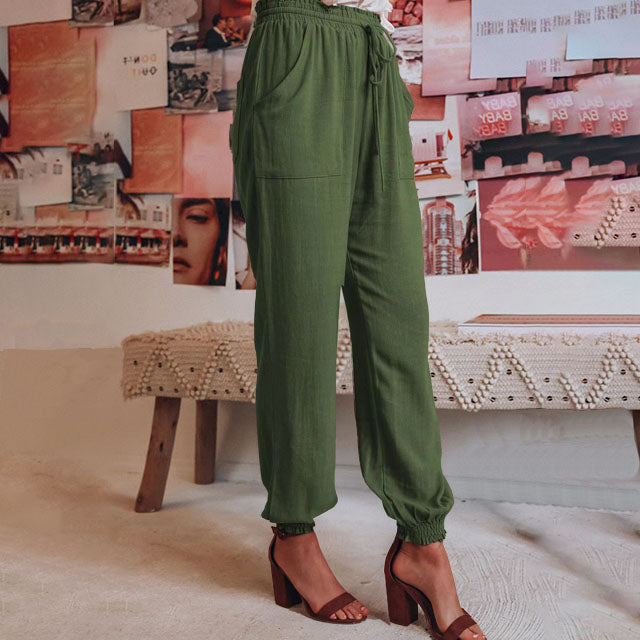 A woman wearing slim tapered black drawstring joggers with a high waist and front patch pockets.