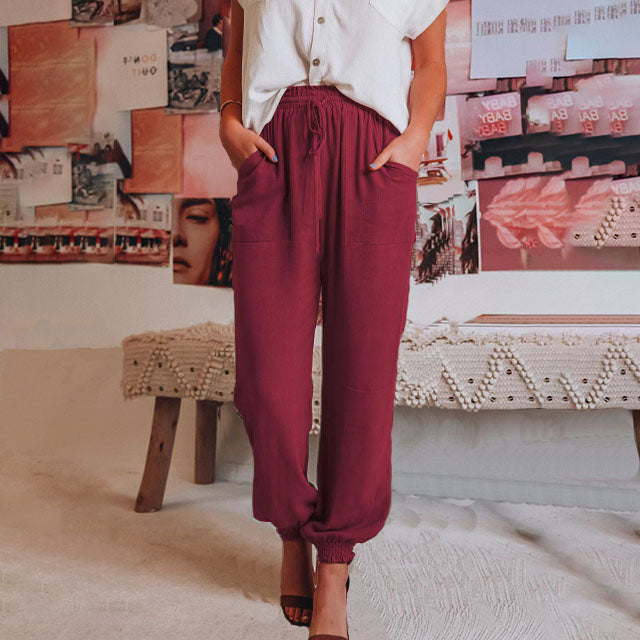 A woman wearing slim tapered black drawstring joggers with a high waist and front patch pockets.