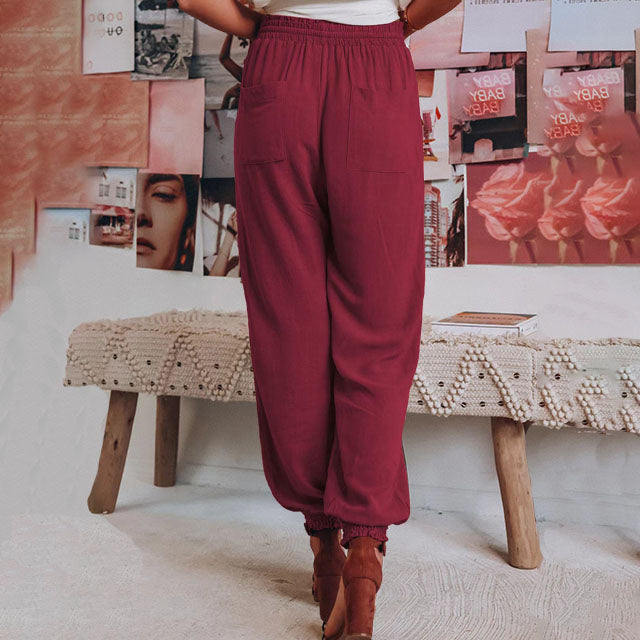 A woman wearing slim tapered black drawstring joggers with a high waist and front patch pockets.