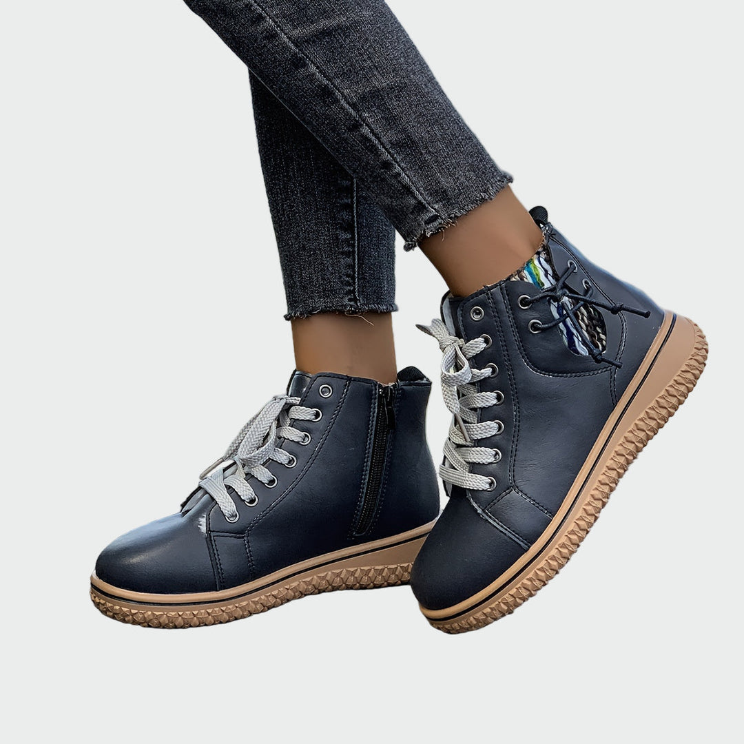 Woman wearing black sporty ankle boots with grey laces, walking through town.