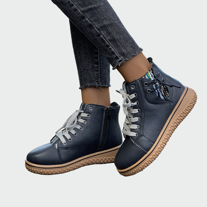 Woman wearing black sporty ankle boots with grey laces, walking through town.