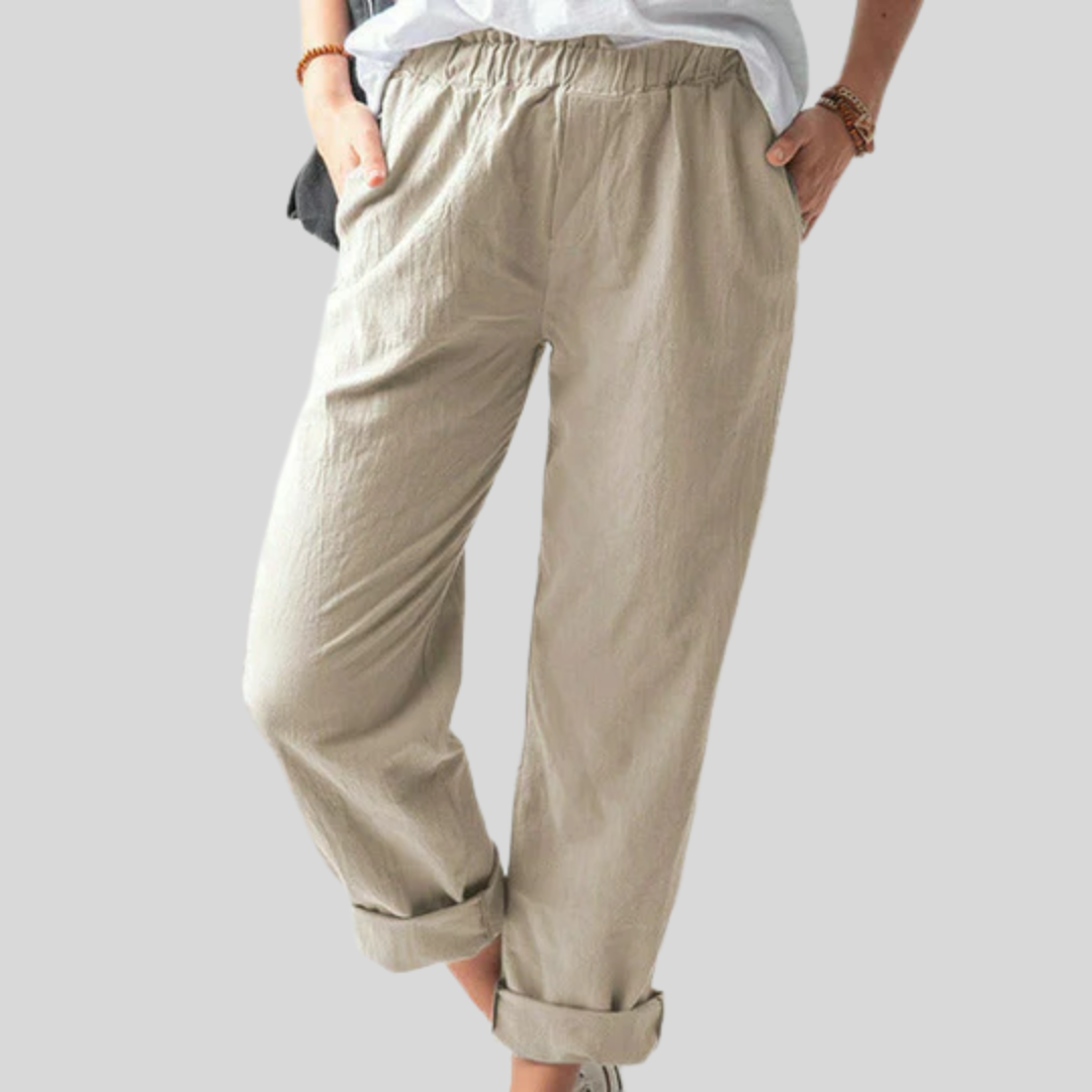 A woman standing relaxed in soft straight-leg pants with a clean, elegant everyday look.