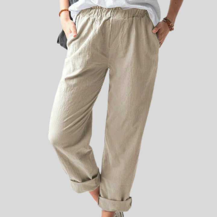 A woman standing relaxed in soft straight-leg pants with a clean, elegant everyday look.