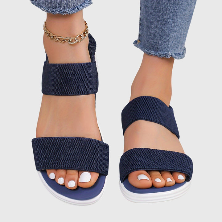 Black open-toe everyday sandals with wide stretch straps and a thick cushioned sole.