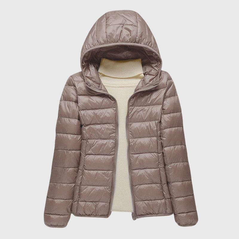 A woman wearing a lightweight padded jacket with a hood, outdoors on a cool day