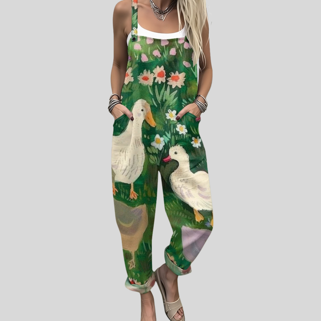 Woman wearing rich green overalls printed with white ducks among grasses and meadow flowers, smiling.