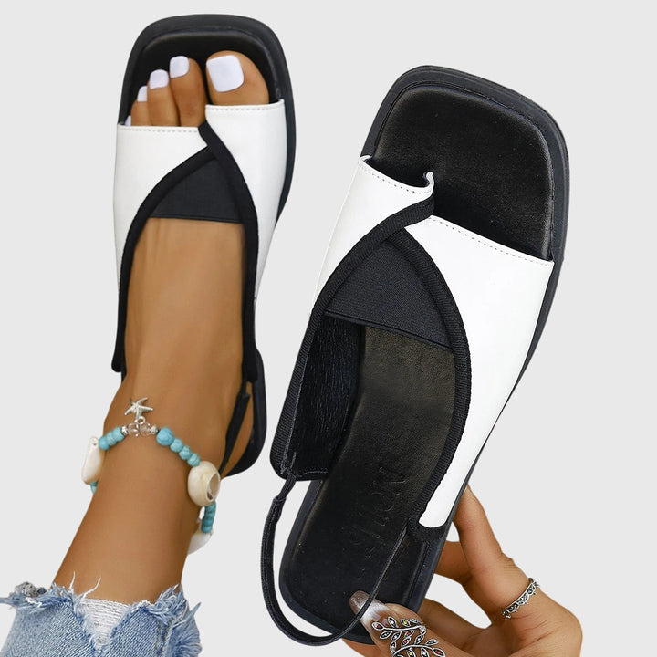 A woman wearing bold two-tone slide sandals on a warm city break.