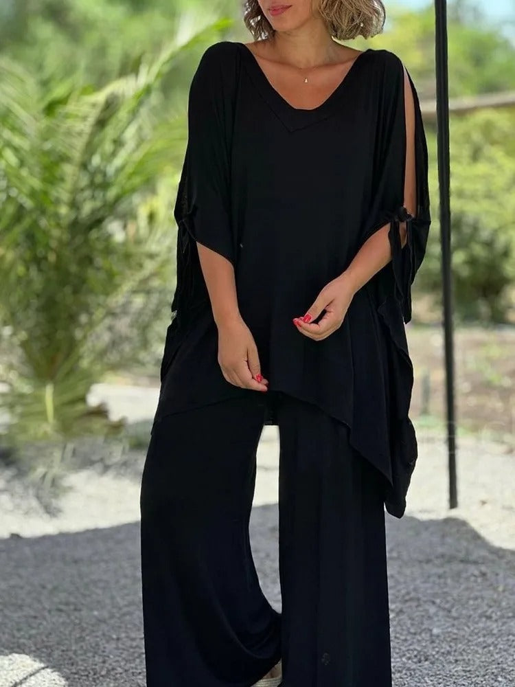 A woman wearing a draped top with shoulder cut-out details and matching wide pants.