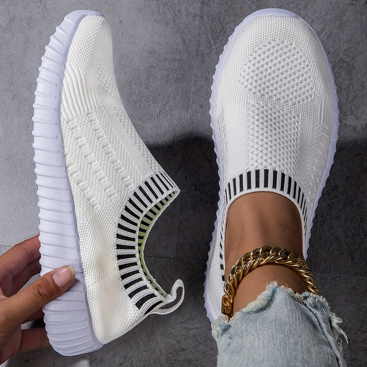 A woman slipping on ultralight sock-style sneakers that hug the foot.