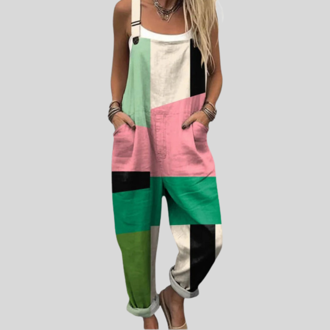 A woman wearing overalls with a graphic patchwork in mint, pink, black and cream, standing confidently in town.