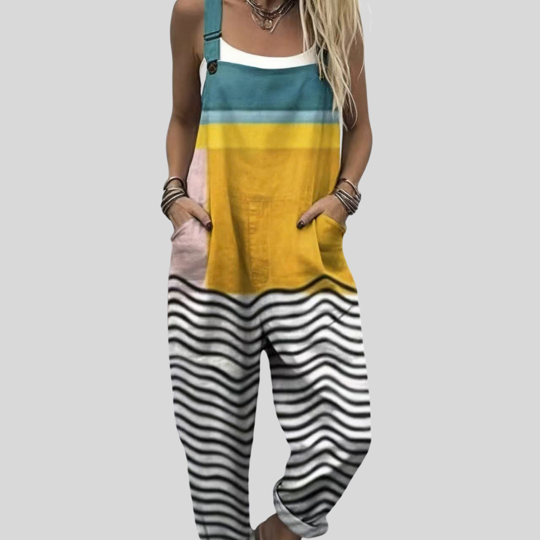 A woman wearing colour-block overalls in teal and yellow with wavy black-and-white detail down the leg, smiling on a bright day.