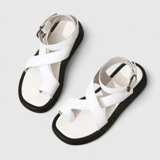 A woman walking comfortably in beige cushioned cross-strap sandals with an adjustable ankle buckle.