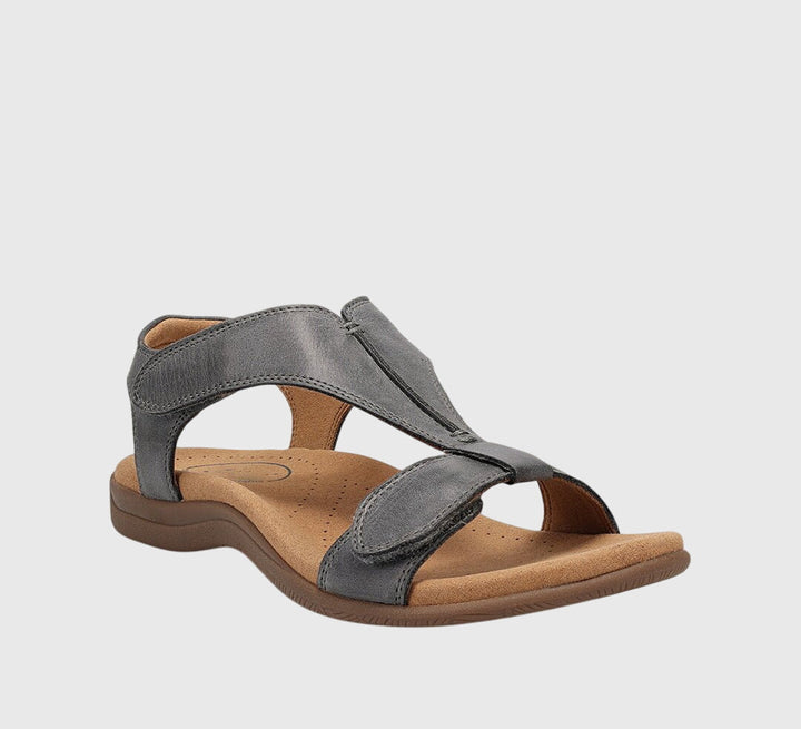A woman wearing T-strap comfort sandals with a summer dress, looking relaxed and elegant.