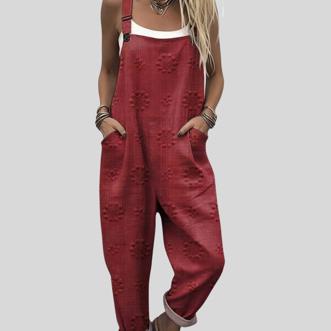 A woman wearing relaxed wine-red overalls with raised tone-on-tone flower motifs and a white top.