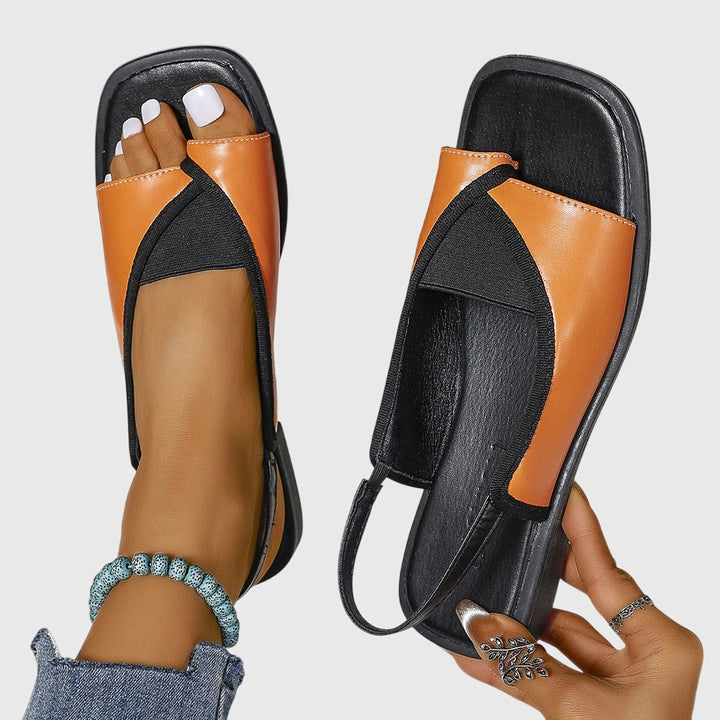A woman wearing bold two-tone slide sandals on a warm city break.