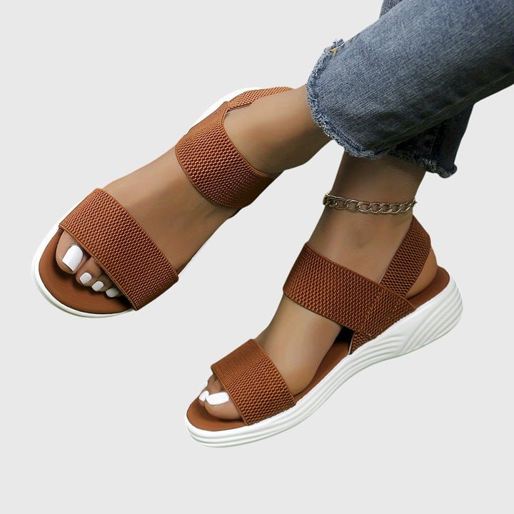 Black open-toe everyday sandals with wide stretch straps and a thick cushioned sole.