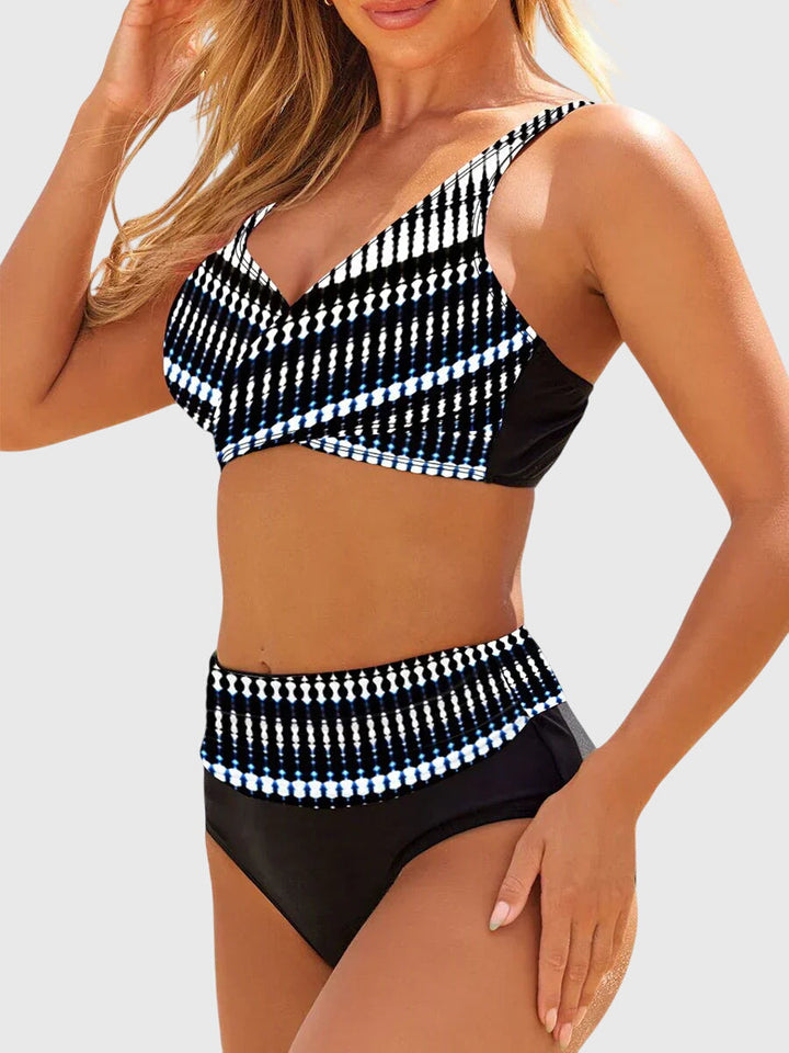 A woman standing by the water in a bold printed two-piece bikini, relaxed and confident in the sun.