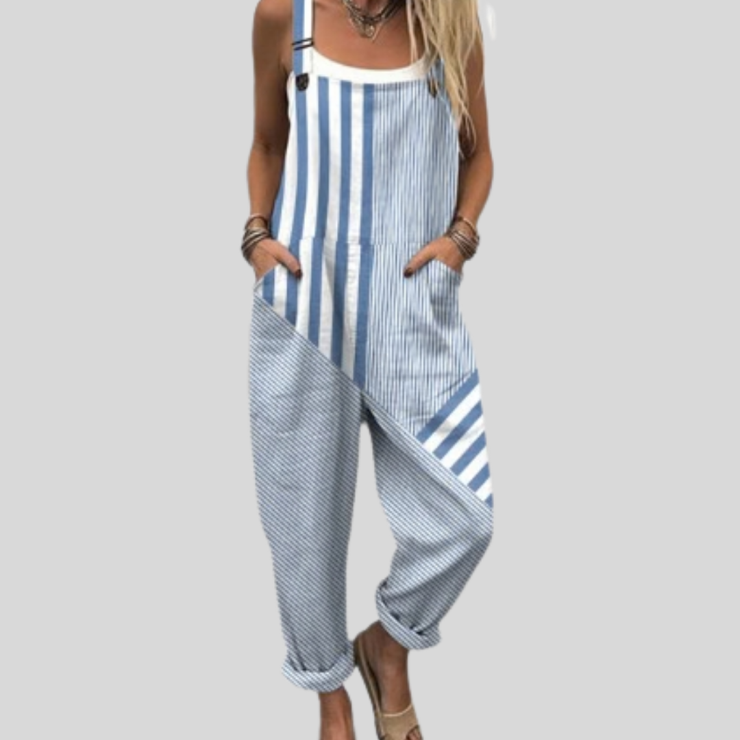 A woman wearing fresh blue-and-white striped overalls on a seaside walk.