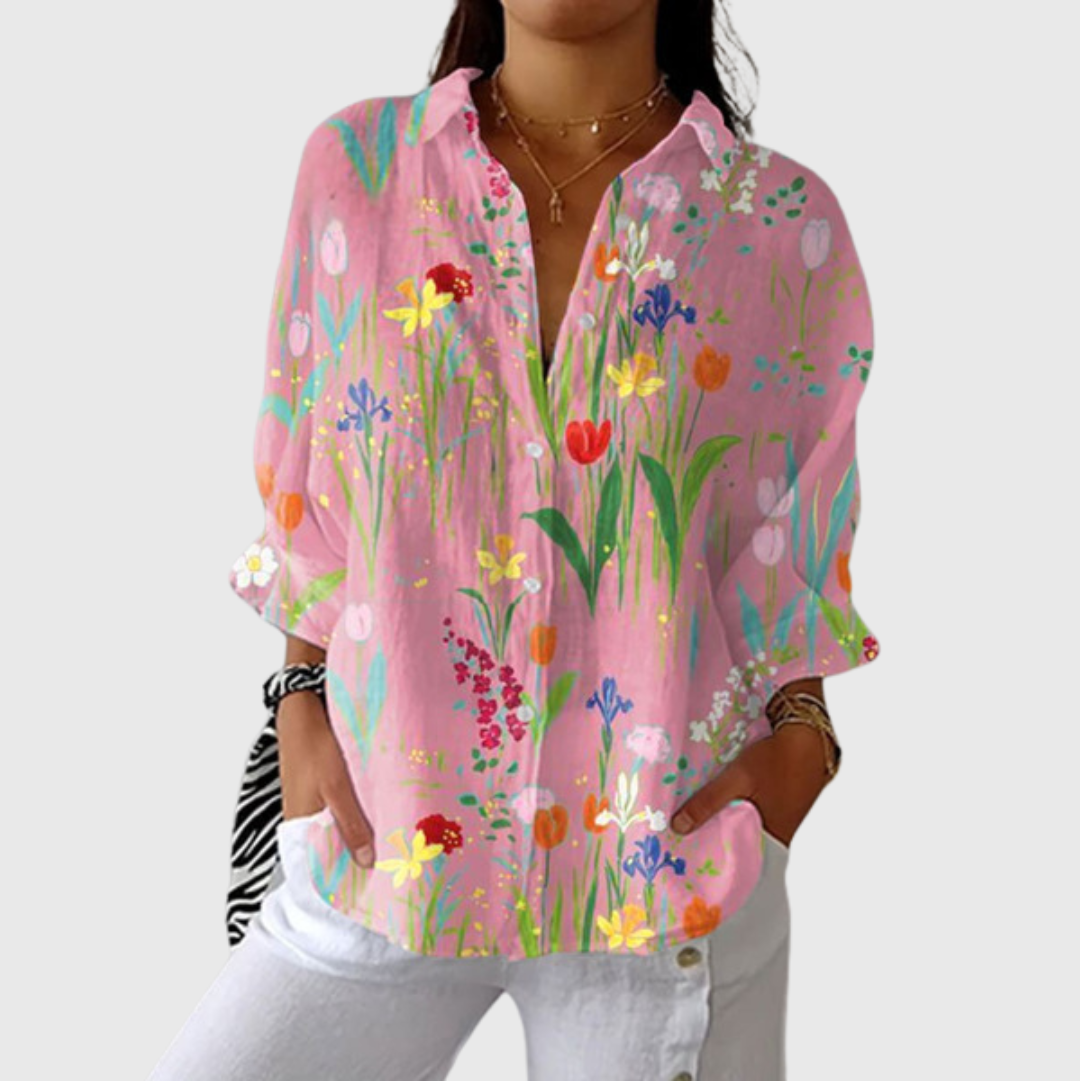 A woman wearing a flowing colourful printed blouse with an elegant button front, styled with a skirt for a relaxed outing.