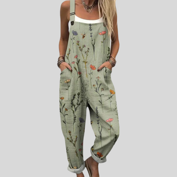 A woman in sage green overalls with a delicate wildflower print, a white top and sandals.