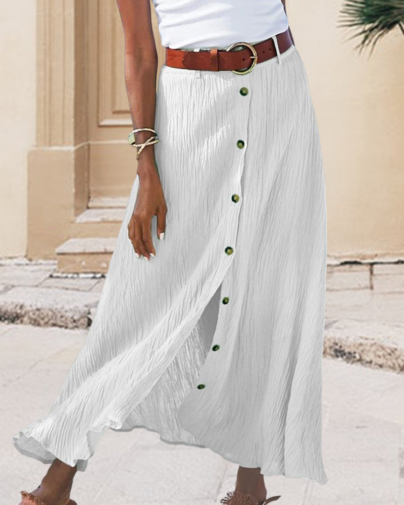 Woman wearing a flowing high-waisted button skirt with a tucked-in top, walking outdoors.