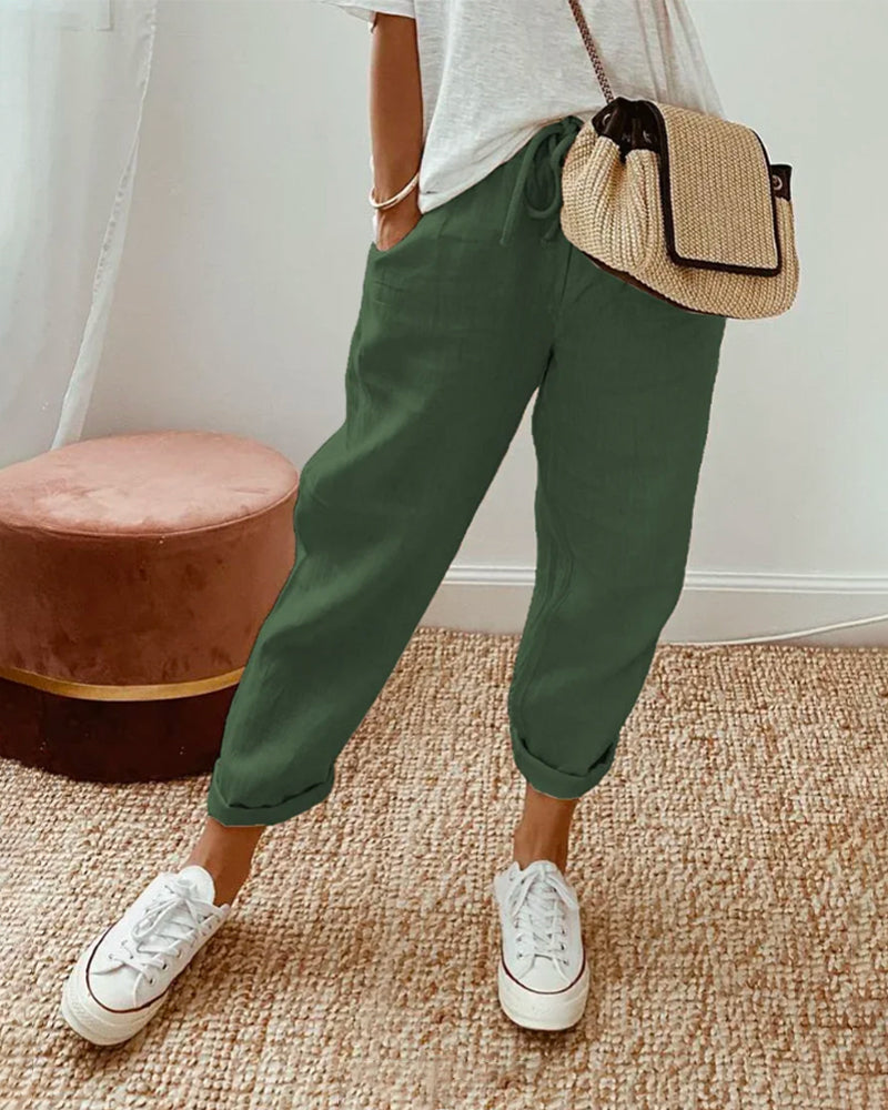 A woman wearing flowing elegant pants with a soft elastic waist and deep pockets.