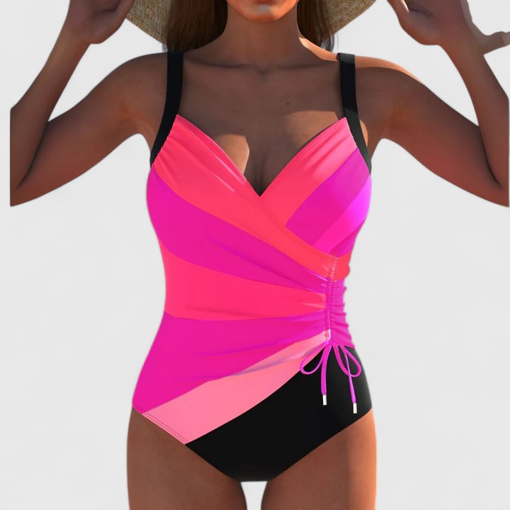 A woman by the water in an elegant printed swimsuit, poised and confident in the summer sun.