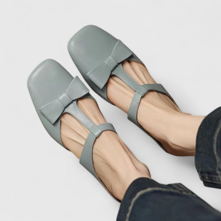 Soft green bow-detail mules with a slim T-strap, open back and a low heel.