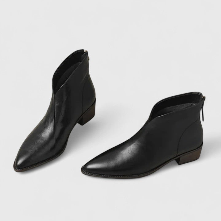 Woman wearing black elegant boots with tailored pants on a city footpath.