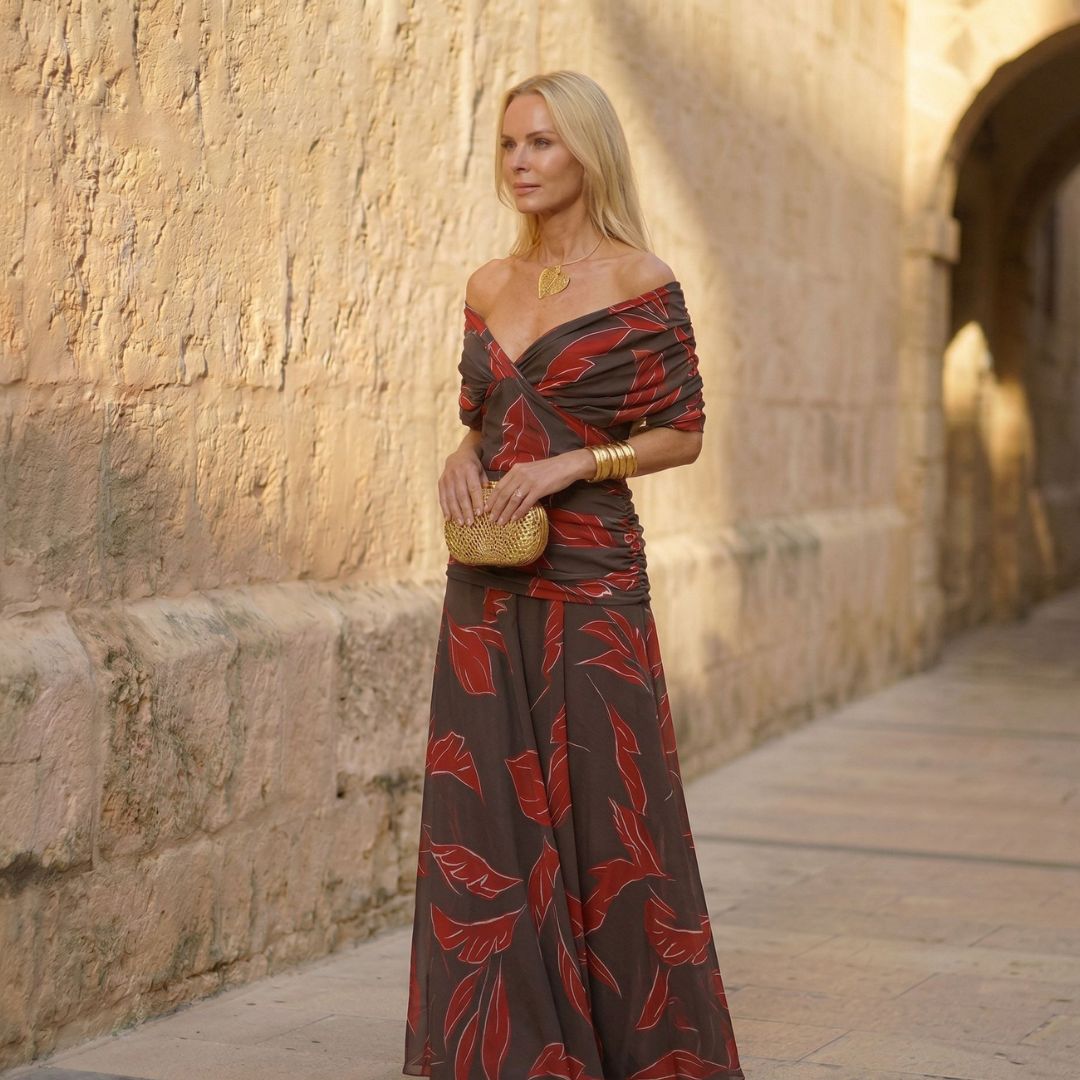 A woman wearing a flowing brown dress with a rust-red leaf print at an occasion.