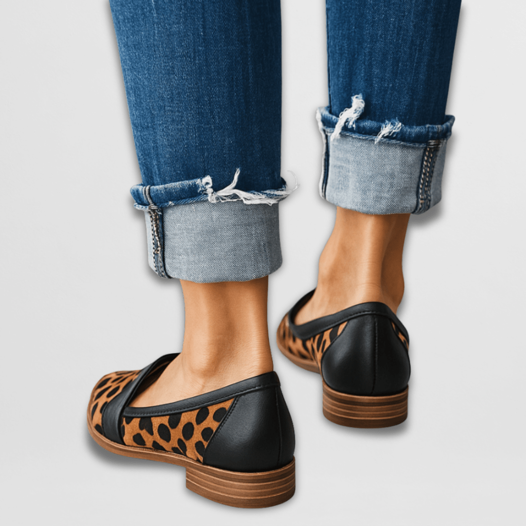 A woman wearing warm tan pointed-toe loafers with cuffed cropped jeans.