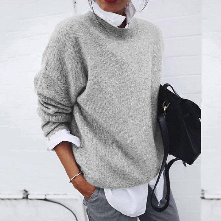 A woman wearing a soft mustard round-neck sweater with an elegant modern shape, relaxed and warm.