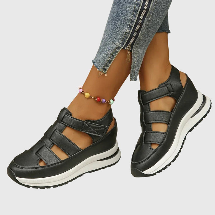 A woman in black cut-out walking sandals exploring a city on a warm day.