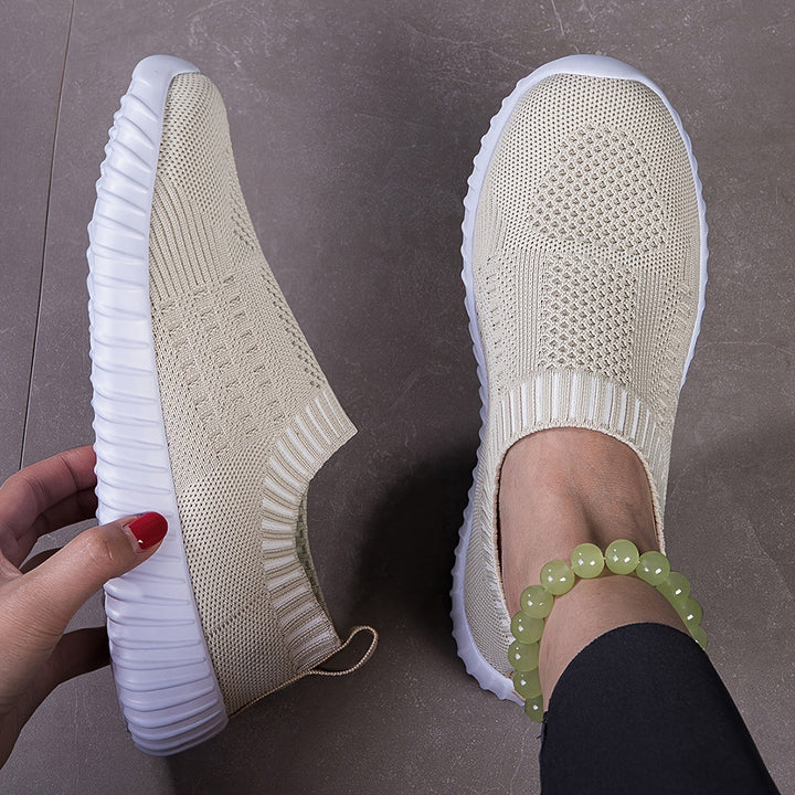 A woman slipping on ultralight sock-style sneakers that hug the foot.