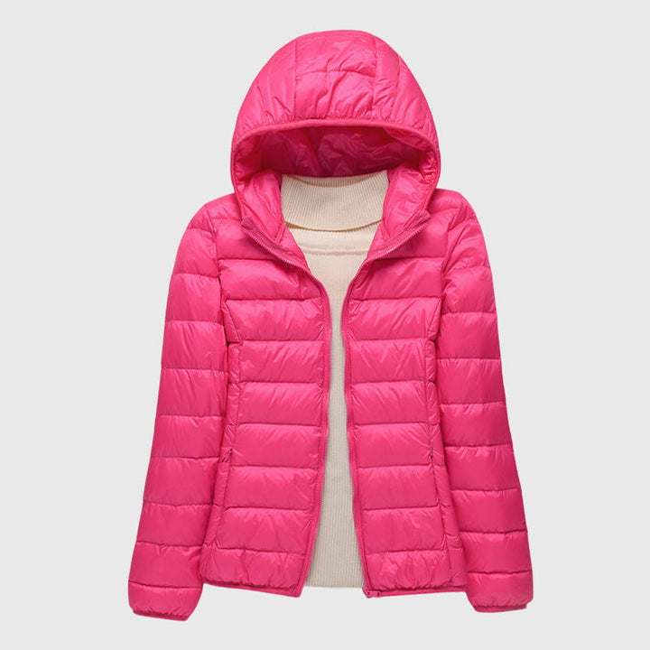 A woman wearing a lightweight padded jacket with a hood, outdoors on a cool day