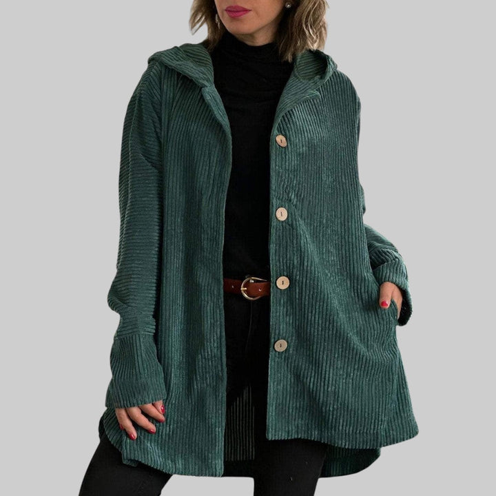 A woman wearing a hooded textured jacket outdoors in fall