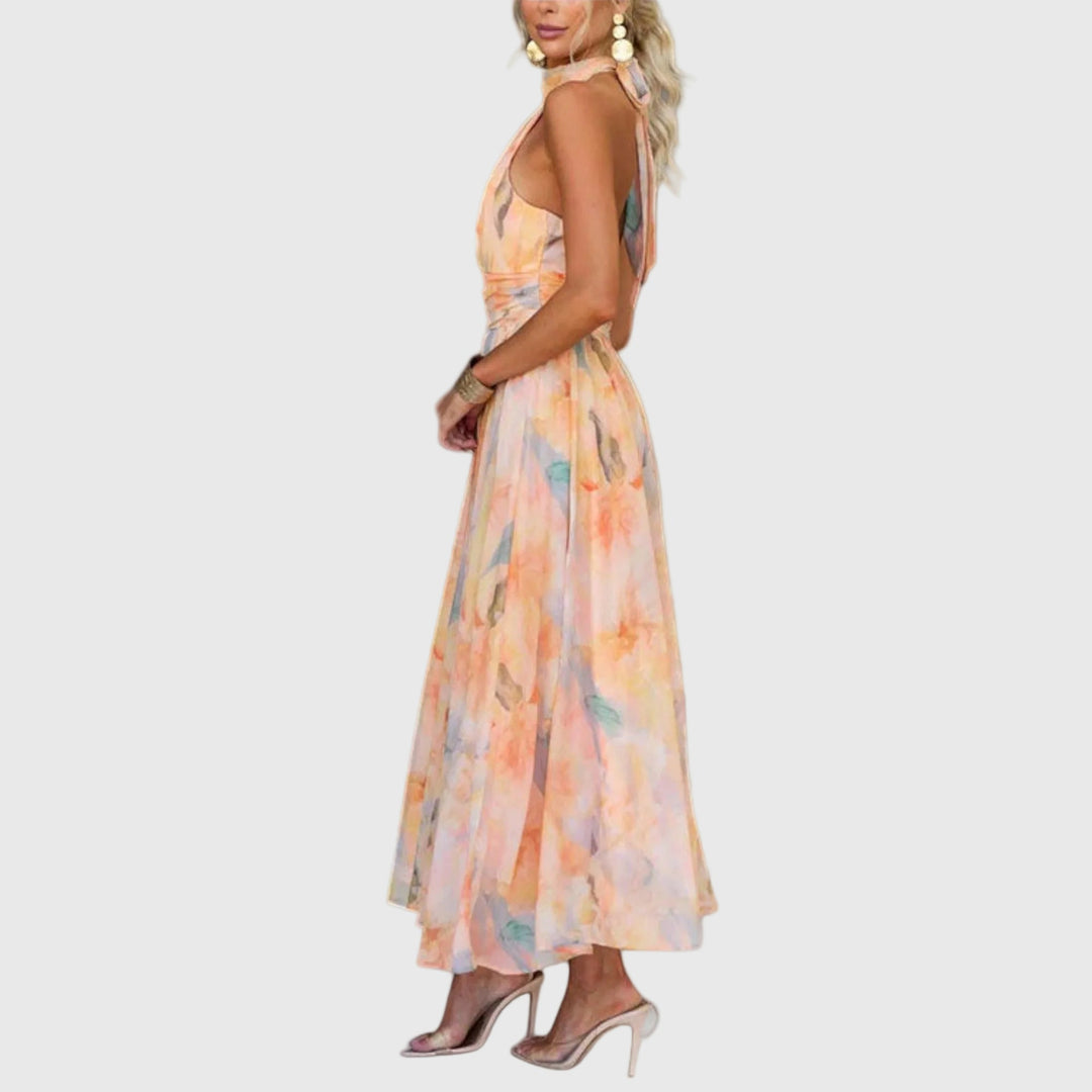 Woman wearing the Carol halterneck maxi dress in warm watercolour tones at an outdoor celebration.