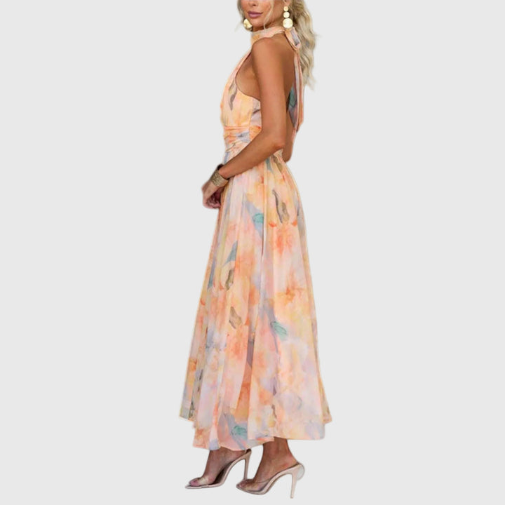 Woman wearing the Carol halterneck maxi dress in warm watercolour tones at an outdoor celebration.