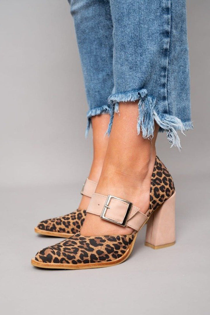 A woman wearing leopard-print pointed heels with a neutral buckled strap and block heel, stepping out in a polished outfit.