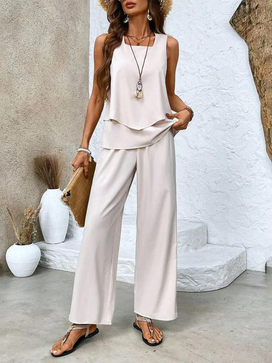 A woman wearing a layered sleeveless top with leaf-print wide-leg pants, light and elegant.